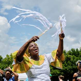 African American woman in traditional dress waving ribbons in the sky