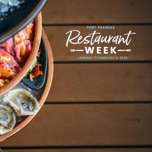Three tier cold bar seafood platter rests on a brown wooden table. A white logo overlaid reads "Port Aransas Restaurant Week January 17–February 2, 2025"