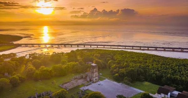 Aerial View of the Cathedral of Our Lady of the Assumption of Panama Viejo. Marine stretch of Cinta Costera in the background. At sunset.