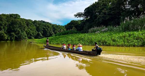 Emberá-Wounaan community traveling by dugout canoe along a river in the Panamanian rainforest
