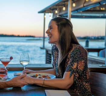 A couple having a waterfront meal in the evening in Southport, NC