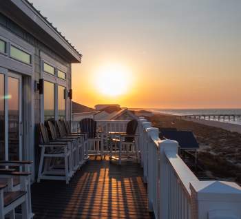 a view of Oak Island and a pier at sunrise from the deck of a vacation rental home