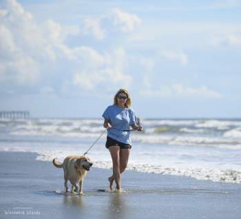 woman walking dog on the beach