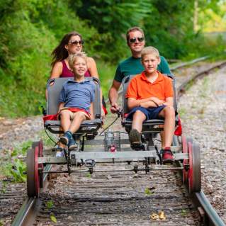 Family of four enjoying the Tracks and Yaks rail biking and kayaking adventure in Allegany County, Maryland, on a sunny summer day.