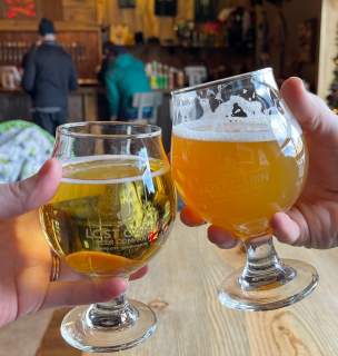 two beers toasting in the lost cabin tap room in rapid city, sd with holiday decor in the background