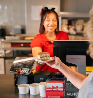 Woman behind the counter working at local lunch spot handing a desert to patron at The Bestro in Rapid City, SD.