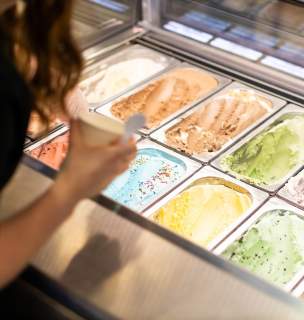 silver lining creamery worker scooping up a cup from the ice cream flavor options in Rapid City, sd