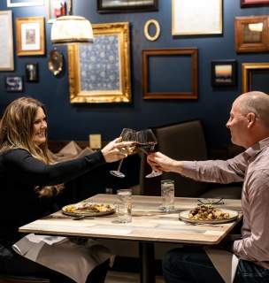 couple cheers-ing wine over a meal at tandoor bocado in downtown rapid city, sd