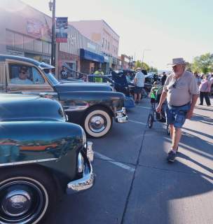 people looking at classic cars parked on the streets of downtown rapid city during the cruiser car show in rapid city, sd