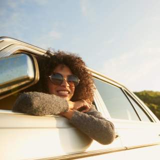 Cropped shot of an attractive young woman leaning out of a car window on a roadtrip