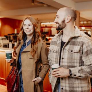 Couple walking through coffee shop with takeway coffees