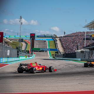 Two formula one cars round the turn in front of fan stands at Austins Circuit of The Americas racetrack