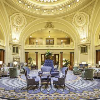 Ornate historical lobby with seating in the middle and a round skylight