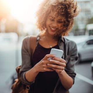 Picture of a young smiling woman using a phone