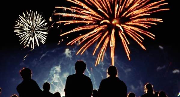 Silhouettes of the backs of people watching colorful fireworks