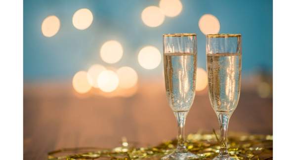 Twochampagne glasses sitting on gold streamers with a blurred out background