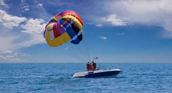 A small boat with a colorful parachute in tow.