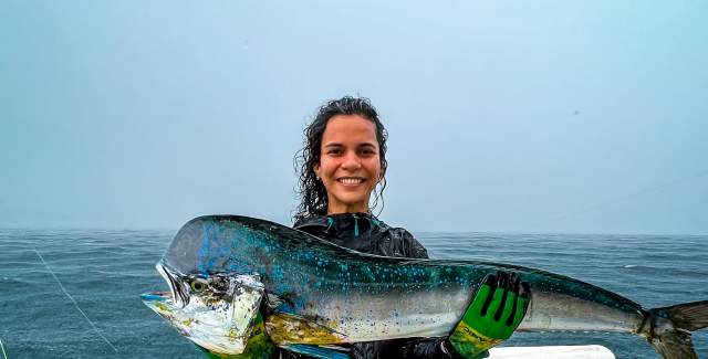 Woman showing the catch of the day, on a boat on a rainy day