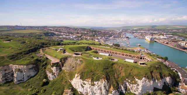 Aerial view of the grounds and red brick buildings of Newhaven Fort with sea in the distance