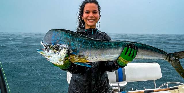 Woman showing the catch of the day, on a boat on a rainy day