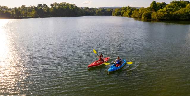 Two kayakers paddling on Sleeter Lake at golden hour, with tree-lined shores in Round Hill Virginia