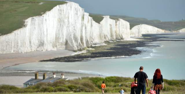 Family walking along coastal path at Seven Sisters, with a view of the sea and white cliffs
