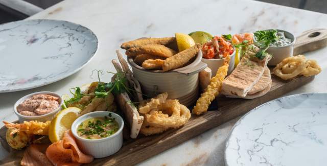 Wooden board with a selection of seafood laid on a marble table top, at Seapearl in Worthing