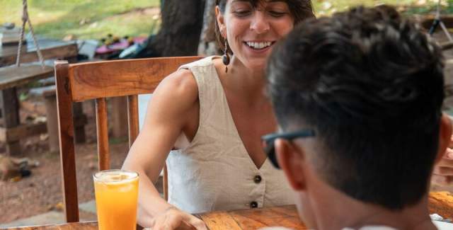 Individuals collaborating to feast on delicious dishes with the ocean as their backdrop.