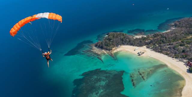 Aerial view of Man paragliding over Contadora island, beautiful blue sky and crystal waters on the view