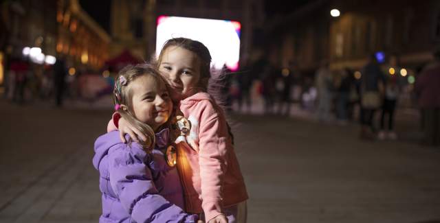 Two children embracing near a light installation