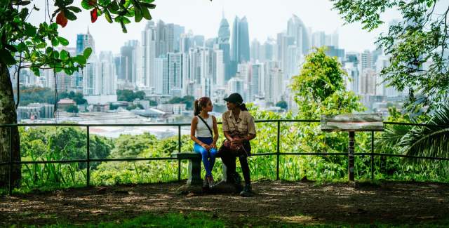 Tourists relaxing at a viewpoint in Metropolitan Natural Park with the Panama City skyline in the background.