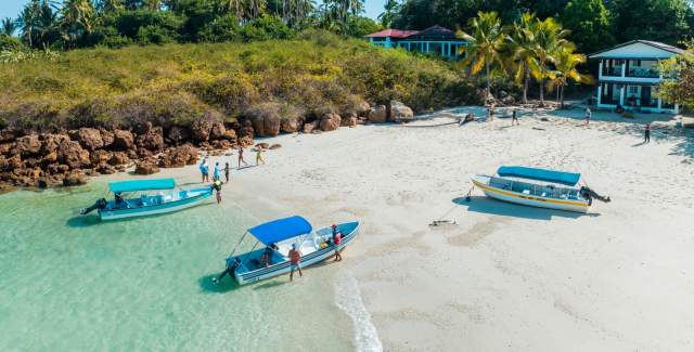 People congregated close to the waterfront of the beach with boats