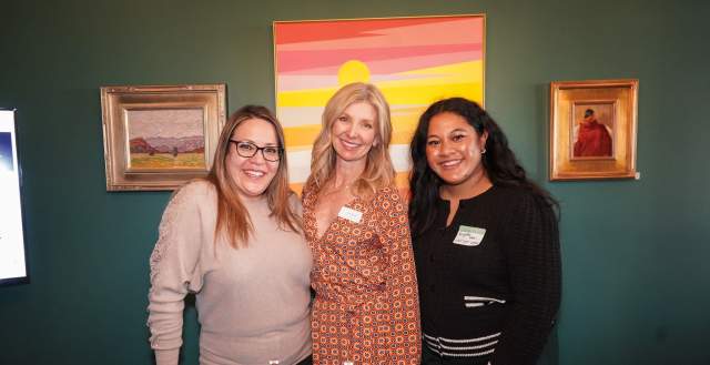Three women standing close together and smiling