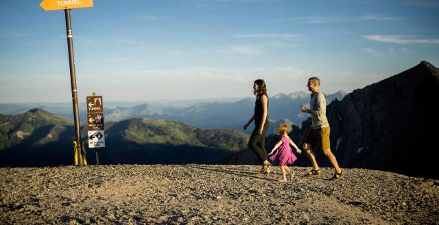 A happy family hiking on top of a mountain with ski trail sign markings