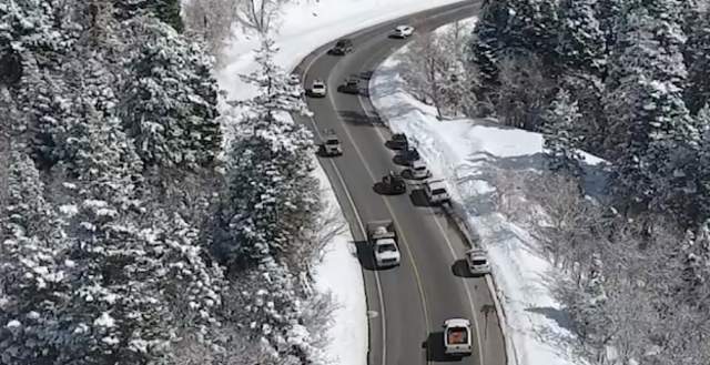 Cars driving on a slightly wet road in a snowy canyon