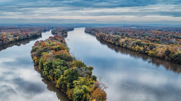 Fall foliage along the Potomac River and a tree-covered island seen from aerial view at Algonkian Regional Park in Sterling