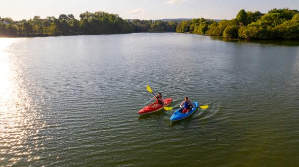 Two kayakers paddling on Sleeter Lake at golden hour, with tree-lined shores in Round Hill Virginia