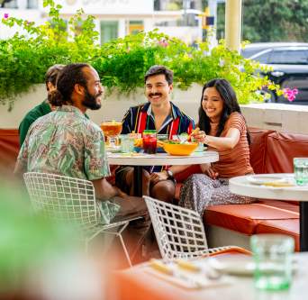 Image of a group of men and women sitting at a table smiling at one another on the patio at Joann's.