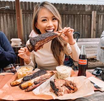 Woman bites into bbq ribs at la Barbecue food truck in Austin Texas