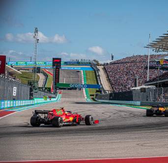 Two formula one cars round the turn in front of fan stands at Austins Circuit of The Americas racetrack