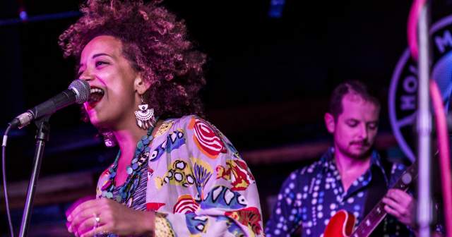 KP & The Boom Boom singer on stage with a guitarist playing behind her