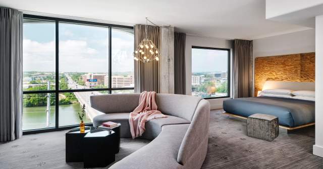 Large, modern hotel room with floor to ceiling windows overlooking Congress Avenue Bridge.