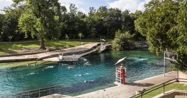 People swimming in Barton Springs Pool with lifeguard in stand