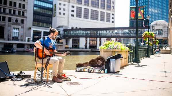 a male busker playing guitar on the Milwaukee RiverWalk