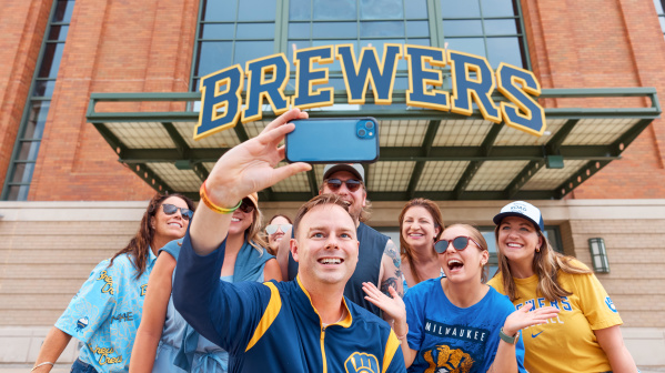 A group of Brewers fans smile in front of American Family Field