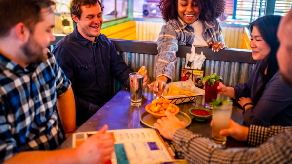 people sitting around a table, eating cheese curds