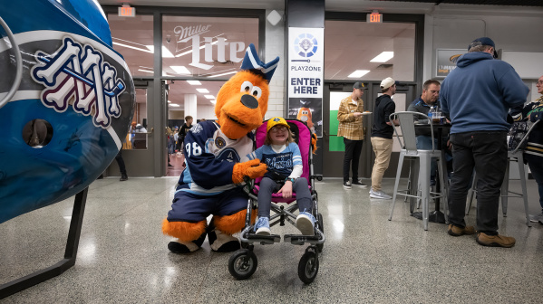 The Milwaukee Admirals mascot, Roscoe, with a young fan in a wheelchair.