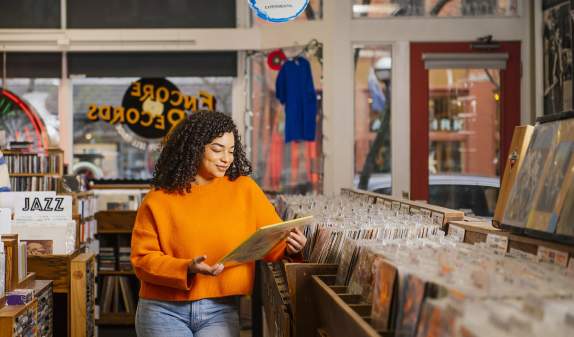 Encore Records- Woman in orange shirt looking at albums in a record store.