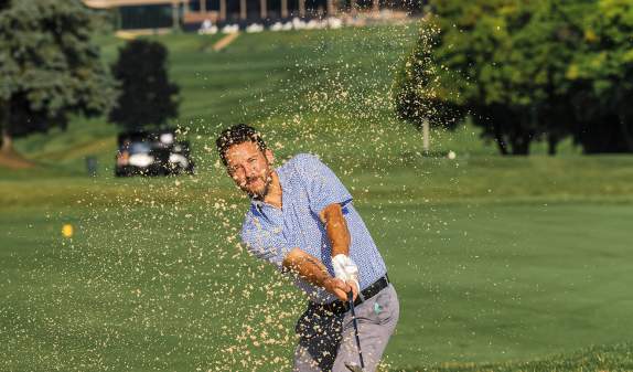 Man hitting golf shot out of sand