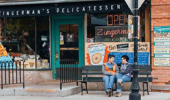 Female couple sitting on bench outside Zingerman's deli